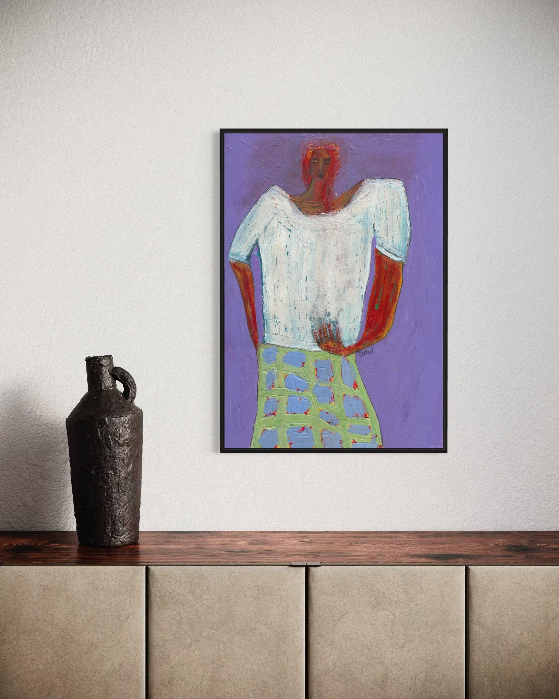 Framed abstract painting on a wall above a wooden shelf with a vase.