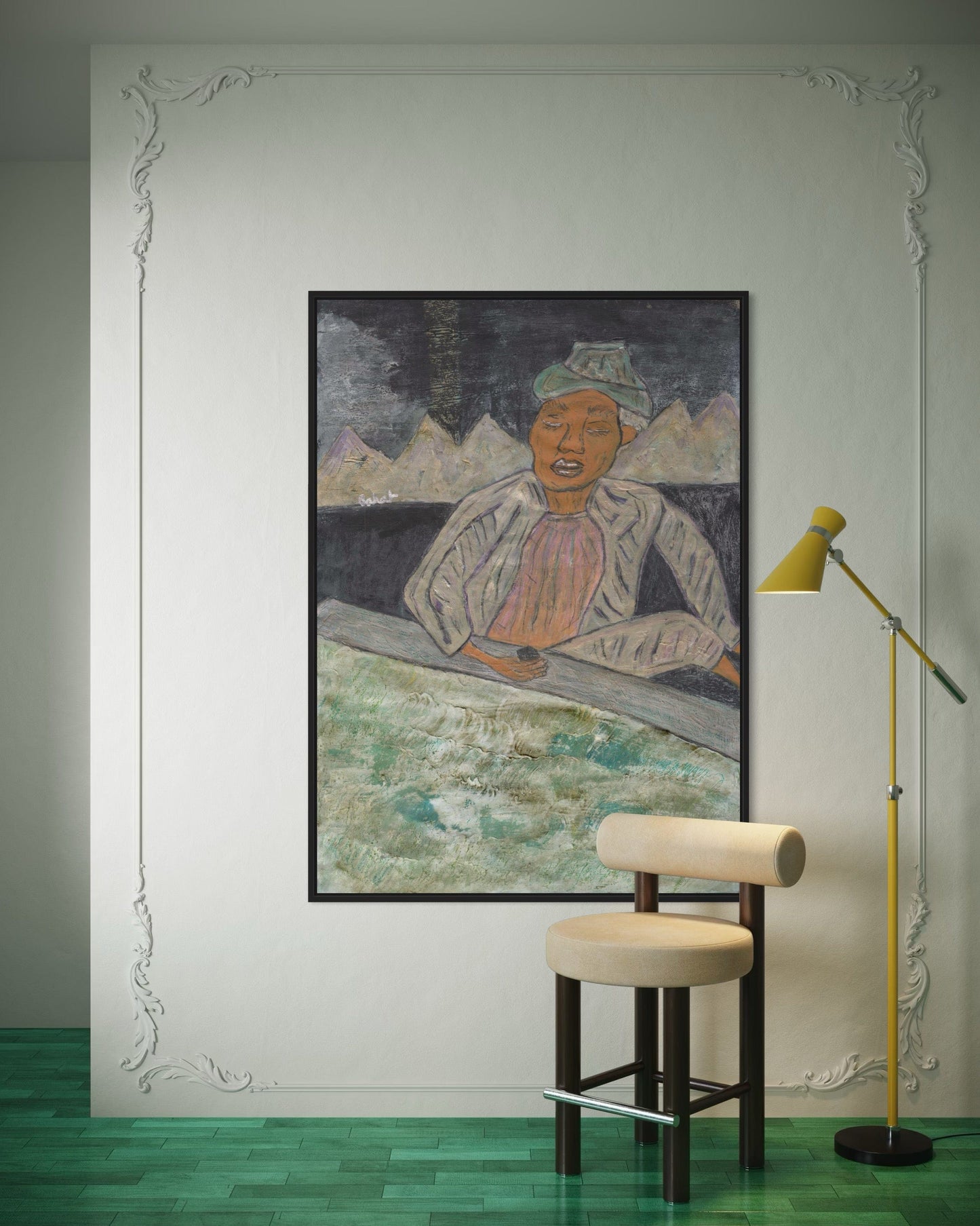 Framed artwork on a wall with a stool and lamp in a room.
