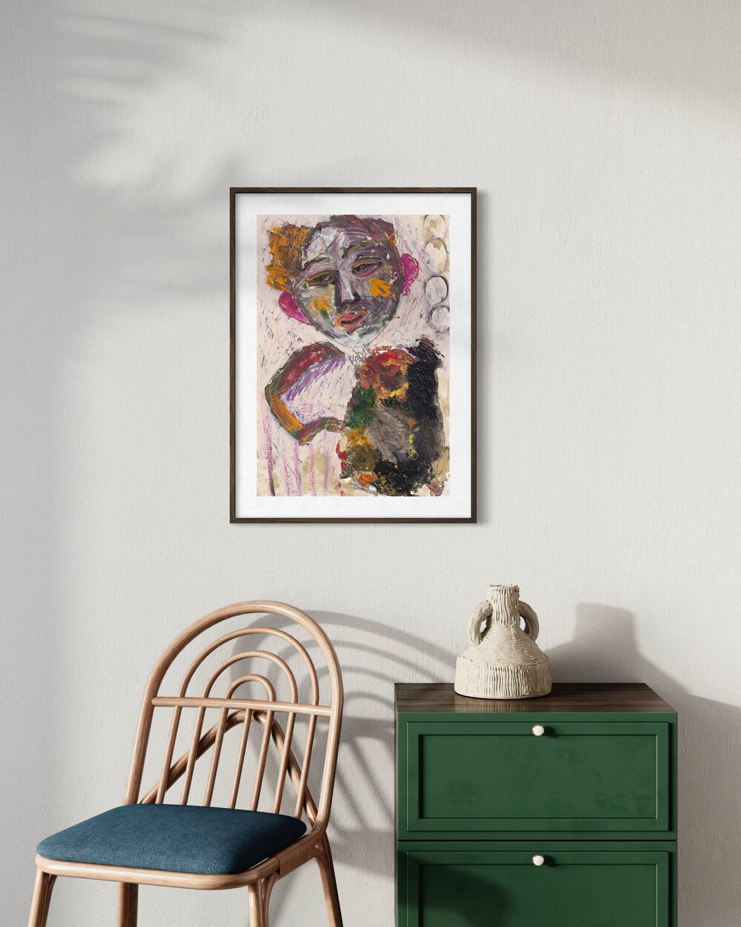 Framed abstract art on a wall above a chair and green cabinet.