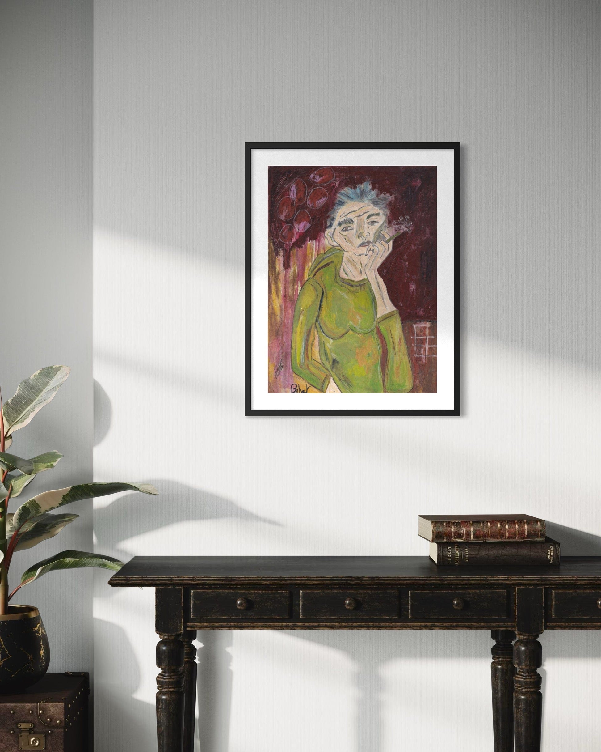 Framed artwork of a person with a mustache on a wall above a dark wooden table.